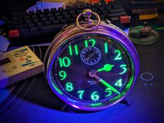 an alarm clock sitting on top of a desk next to a keyboard