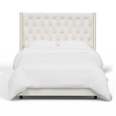 a white bed with a tufted headboard and pillows on it's sides