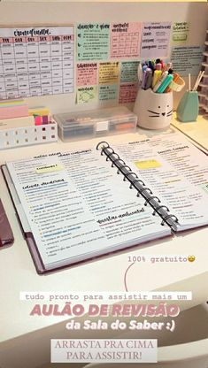 an open notebook sitting on top of a desk next to a pen and pencil holder