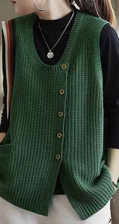 a woman wearing a green sweater vest with buttons on the front and back, while she is