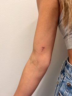 a woman's arm with a small cross tattoo on the left side of her arm