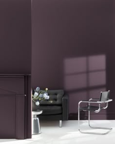 a living room with purple walls and a black leather chair in front of the couch