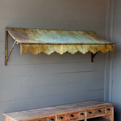 a bench and table in front of a wall with a metal awning over it