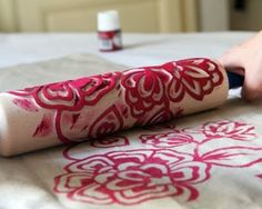 a person is using a sharp knife to paint the fabric on a bed sheet with red and white designs