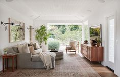 a living room filled with furniture and lots of plants on the wall next to it