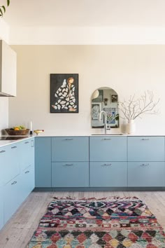 a kitchen with blue cabinets and rug on the floor in front of an area rug