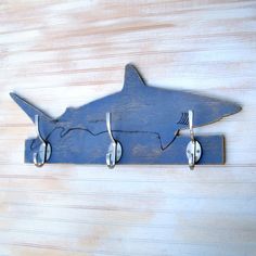 three hooks hang on the side of a wooden wall with a shark shaped coat rack