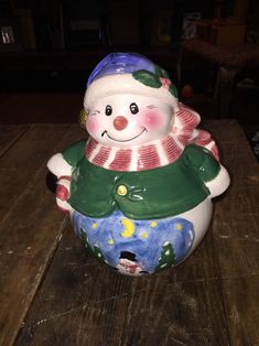 a ceramic snowman sitting on top of a wooden table