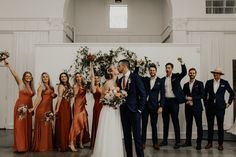 a group of people standing next to each other in front of a wall with flowers