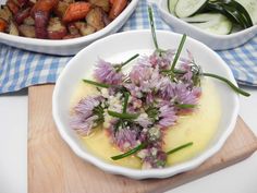 two bowls filled with food on top of a wooden cutting board next to other dishes