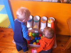 two toddlers playing with plastic balls in a play room at home or school,