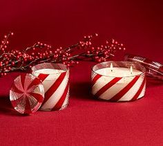 two red and white striped candles sitting next to each other on top of a table