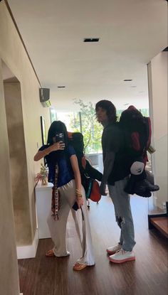 two women are standing in the hallway with backpacks on their backs and one is taking a selfie