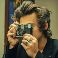 a person taking a photo with a camera in front of their face and wearing rings