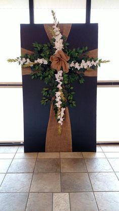 a cross decorated with white flowers and greenery