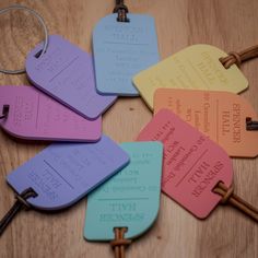 six different colored luggage tags sitting on top of a wooden table next to two keys