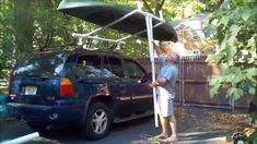 a man standing next to a car with a boat on top of it's roof