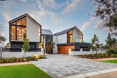 a modern house with large windows and lots of greenery in the front yard area