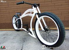 a white and black bicycle parked in front of a brick wall