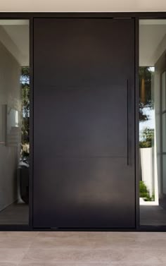 an open black door with glass on the inside and outside, in front of a white wall