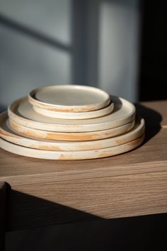 stack of white plates sitting on top of a wooden table