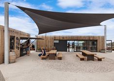 people are sitting on benches under an awning