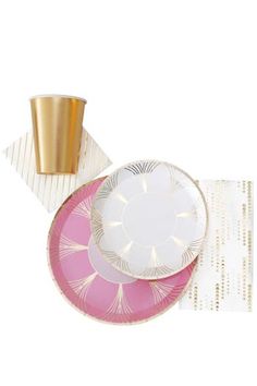 pink and white plates with gold rims next to a cup on a tablecloth