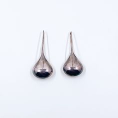 The listing is for a pair of Vintage Silver Modernist Drop Earrings. The earrings feature a simple hollowed domed rain drop design. The earring and ear wire are all one piece. They are for pierced ears. Weight: 6.4 grams  Measurements: approximately 1.8440 inches long and 0.7610 inches wide Marks: There are some unidentified marks on the inside of the ear wire. Acid test as sterling silver.  The earrings have patina and can be cleaned by buyer if preferred.  ❤All items in my shop are Estate, Vin Pierced Metal Drop Earrings, Pierced Drop Metal Earrings, Metal Teardrop Drop Earrings, Metal Teardrop Pendant Earrings, Modern Pierced Drop Teardrop Earrings, Modern Teardrop Pendant Earrings With Ear Wire, Modern Metal Drop Earrings For Pierced Ears, Modern Teardrop Earrings With Crown, Minimalist Teardrop Drop Earrings