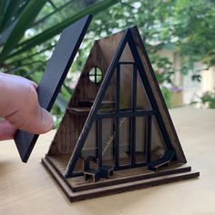 a hand holding a miniature house made out of wood