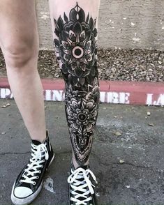 a person with black and white tattoos standing on the street next to their legs wearing tennis shoes