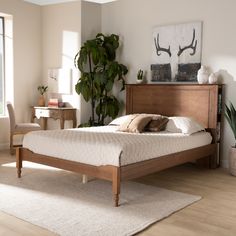 a bed sitting on top of a wooden floor next to a plant in a bedroom