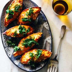 baked potatoes with spinach and cheese on a plate next to a glass of wine