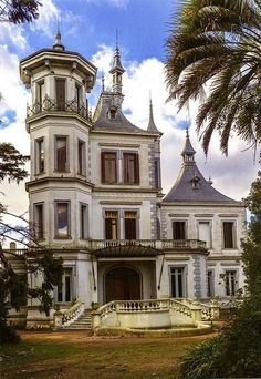 an old house with many windows and balconies on the front, surrounded by palm trees