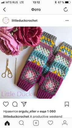 two crocheted mittens sitting on top of a table next to a pink flower