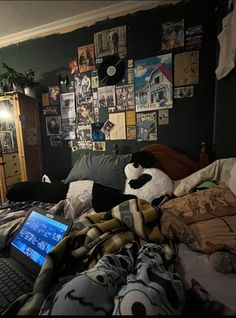 a laptop computer sitting on top of a bed next to a pile of blankets and pillows