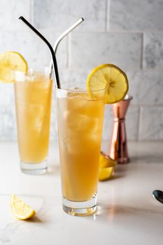 two glasses filled with lemonade sitting on top of a counter