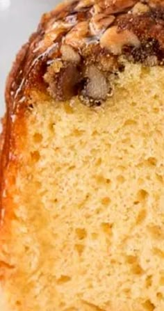 a close up of a piece of cake on a white plate with nuts and caramel sauce