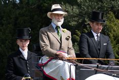 two men and a woman riding in an old fashioned horse drawn carriage with hats on