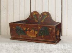 an old wooden box with roosters painted on the front and sides, sitting against a white background