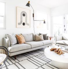 a living room filled with lots of furniture and decor on top of a white rug