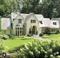 a large white house surrounded by lush green trees and flowers in front of it is an entry way to the home