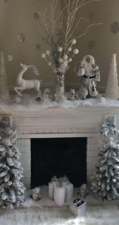 a fireplace decorated for christmas with white decorations and presents on the mantel, surrounded by snow - covered trees