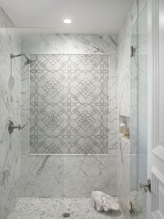 a bathroom with marble walls and flooring in the shower area, along with a glass door