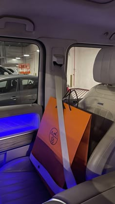 an orange shopping bag sitting in the back seat of a car with its door open