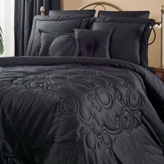 the comforter is black and has an intricate design on it, along with matching pillows