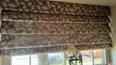 a window with a brown and white patterned blind on it's side, in front of a window sill