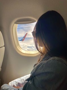 a woman looking out an airplane window at the sky