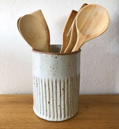 several wooden spoons in a ceramic cup on a table