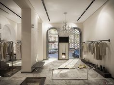 the inside of a clothing store with lots of clothes on racks and chandeliers