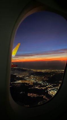 the view from an airplane window at night with city lights in the distance and bright blue sky